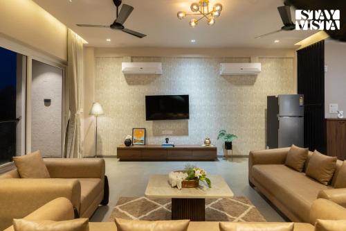 Una sala de estar con dos sofás y un televisor. en StayVista at Zenith Palms, en Igatpuri