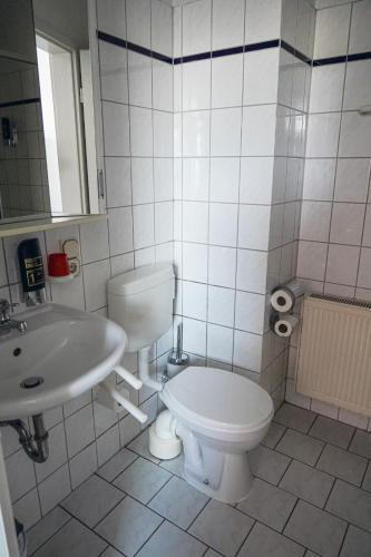 a white bathroom with a toilet and a sink at Apart-Hotel-Pension in Taucha