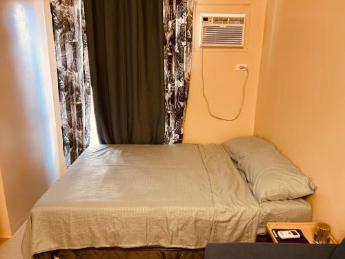 Cama pequeña en habitación pequeña con ventana en Iloilo Staycation, en Iloilo City