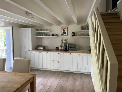 een keuken met witte kasten en een houten vloer bij La Maison Rose in Saint-Armel