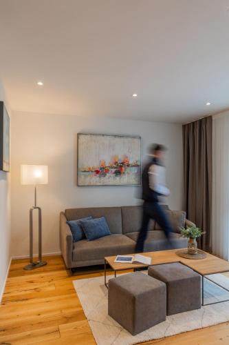 a man walking through a living room with a couch at LMS - La Maison Suisse - Döttingen in Döttingen