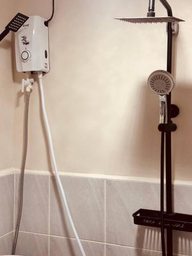 a shower head and a blow dryer in a bathroom at Victoria Suites Mactan in Suba