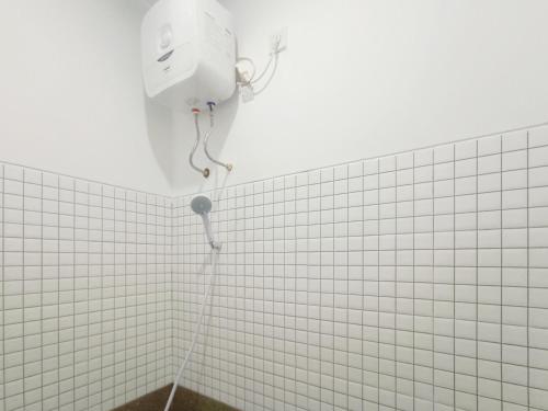 La salle de bains est pourvue d'une douche et d'un mur carrelé blanc. dans l'établissement Ndalem Tamanan Syariah RedPartner, à Gondowulung