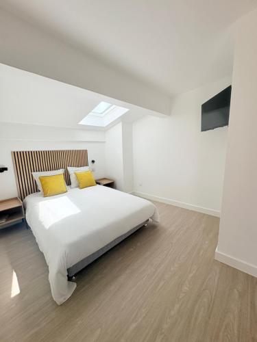 a bedroom with a white bed with yellow pillows at Les chambres du Vignoble in Pauillac
