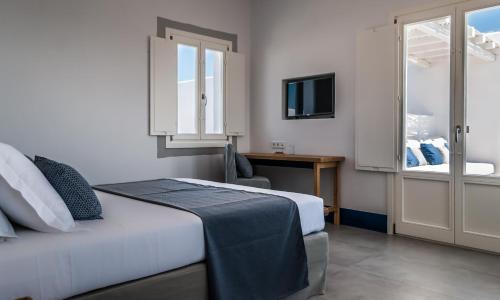 a bedroom with a bed and a desk and a television at Milos Breeze Boutique Hotel in Pollonia