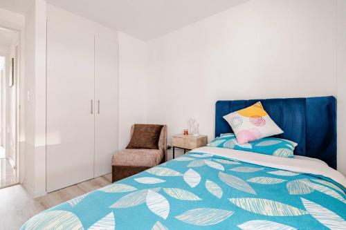 a bedroom with a bed with a blue headboard and a chair at Stylish & Modern 2BR Apartment in Quito