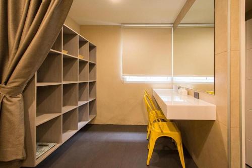 a bathroom with a sink and two yellow chairs at Lazy Sunday hostel in Bangkok