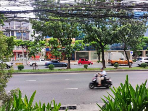 a person riding a scooter down a city street at mstay in Bangkok