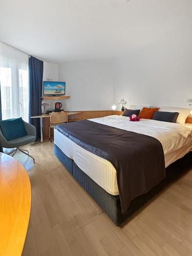a bedroom with a large bed and a chair at Centra Hotel Zurich in Bassersdorf