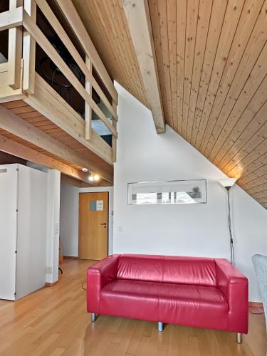 a red couch in a living room with a wooden ceiling at Centra Hotel Zurich in Bassersdorf