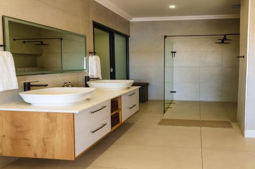 a bathroom with two sinks and a shower at 1442 Marina by Double Portion in Jeffreys Bay