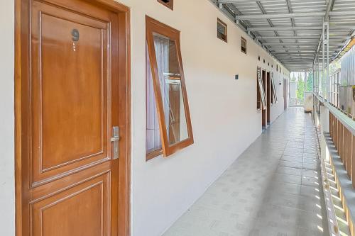 an empty hallway with a wooden door and a hallwayngth at RedDoorz near Treetop Adventure Kopeng in Kopeng