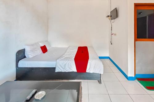 a bedroom with a bed with a red and white blanket at RedDoorz near Treetop Adventure Kopeng in Kopeng
