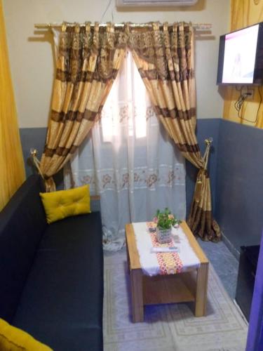 ein Wohnzimmer mit einer Couch und einem Tisch und einem Fenster in der Unterkunft Le Centurion in Brazzaville