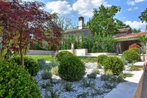 a garden with blue flowers in front of a house at Villa Zita with private pool and sauna in Potpićan
