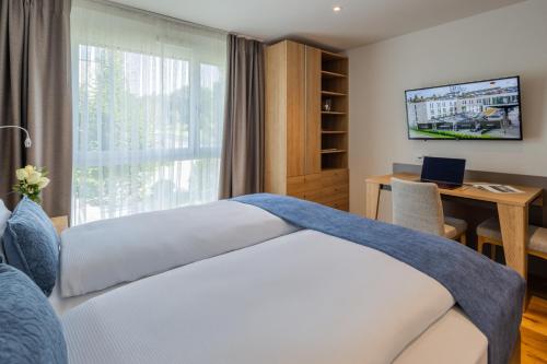 a bedroom with a bed and a desk and a window at LMS - La Maison Suisse - Döttingen in Döttingen