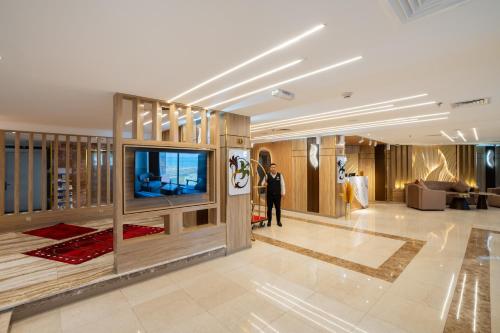 a man is standing in a lobby with a television at Plaza Athenee Hotel in Kuwait