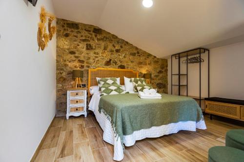 a bedroom with a bed and a stone wall at Pensión Casa a Fontana 