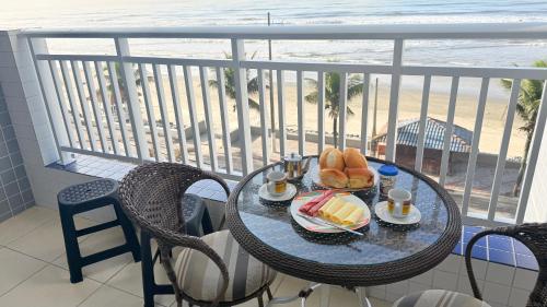 a table with a plate of food on a balcony with the beach at Apto Frente Praia Familiar in Mongaguá