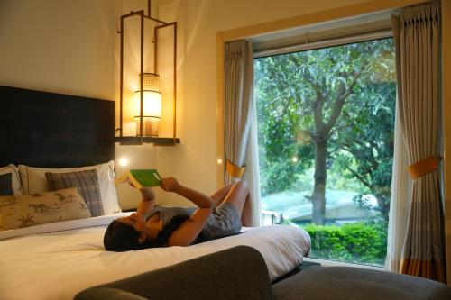 a woman laying on a bed reading a book at The Solluna Resort in Marchula