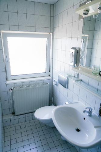 a white bathroom with a sink and a toilet at Apart Hotel Leipzig Taucha in Taucha