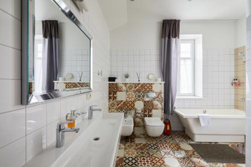 a bathroom with a tub and a toilet and a sink at Lettia Aparthotel in Jūrmala
