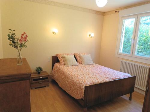 a bedroom with a bed and a vase with flowers on it at Maison dans îlot de verdure in Languidic