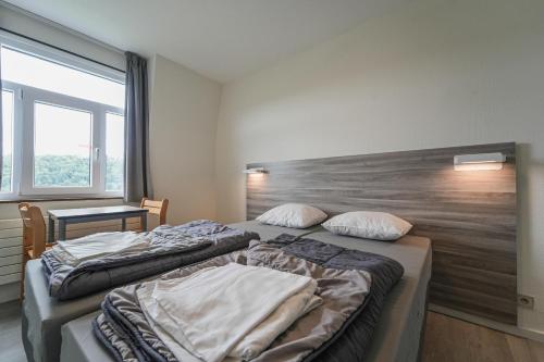 two beds in a room with a large window at Auberge de Jeunesse de Bouillon in Bouillon