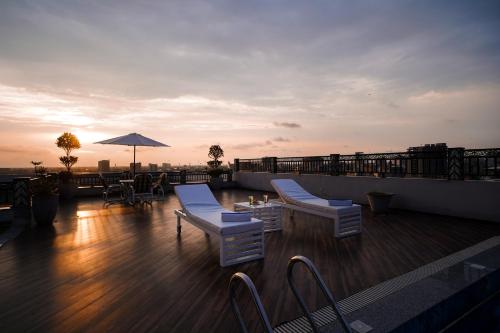 a rooftop deck with chairs and tables and an umbrella at Nine Tree Luxury Hotel & Suites Lahore in Lahore