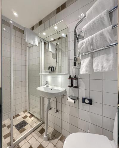 a white bathroom with a sink and a shower at Waxholms Hotell in Vaxholm