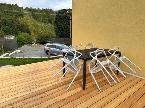 a black table with white chairs on a wooden deck at DOMEK Písařov - apartmány in Písařov