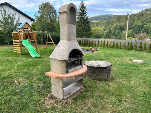 an outdoor oven in a yard with a playground at DOMEK Písařov - apartmány in Písařov