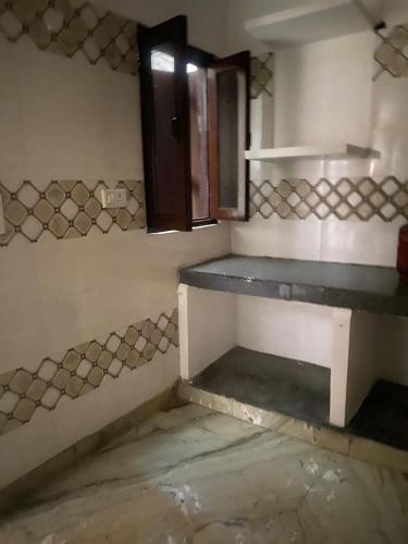 an empty room with a kitchen with a counter and a window at Swamiji niwas in Morādābād
