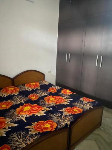 a bed with a blue blanket with flowers on it at Swamiji niwas in Morādābād