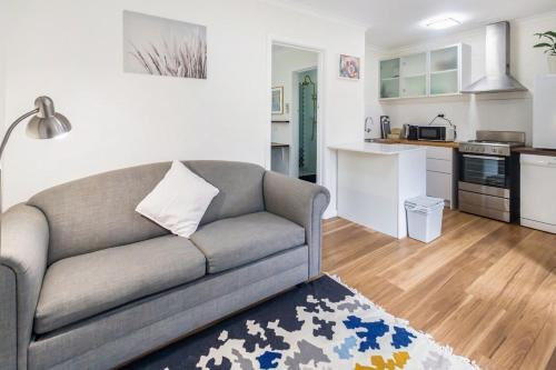 a living room with a couch and a kitchen at Yarralumla Apartment Stay Queen Bed and Sofa Bed Free Parking in Yarralumla