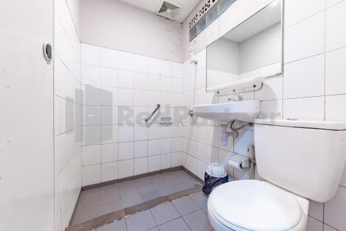 a white bathroom with a toilet and a sink at Yehezkiel Hotel Lembang Mitra RedDoorz in Bandung