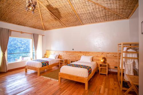 a bedroom with two beds and a large window at Burunga Gorilla Lodge in Kisoro
