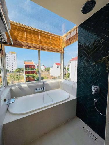 a large bath tub in a bathroom with a large window at Lovela Villa Phan Thiết in Ấp Bình Hưng