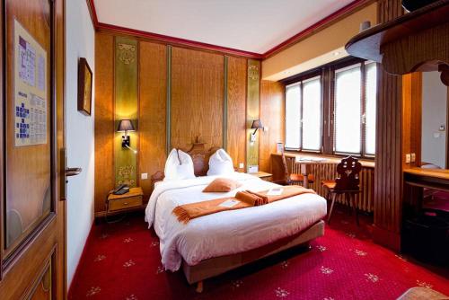 a bedroom with a large bed and a desk in it at Hotel - Restaurant Le Cerf & Spa in Marlenheim