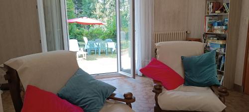 a living room with two chairs with pillows on them at Maison dans îlot de verdure in Languidic
