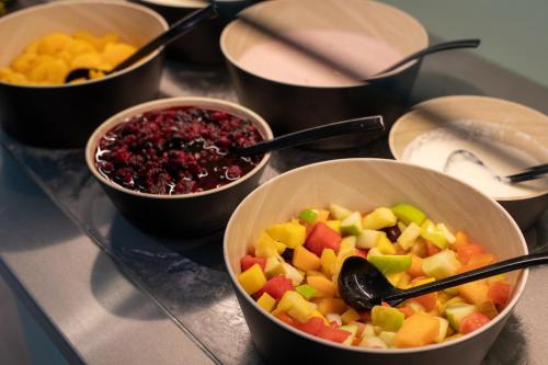 a group of bowls of fruit on a table at MEININGER Hotel Berlin Airport in Berlin