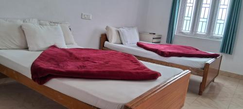 two beds with red blankets on them in a room at Grace Cottage in Ooty