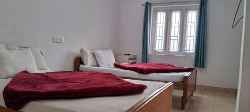 a room with two beds with red blankets on them at Grace Cottage in Ooty