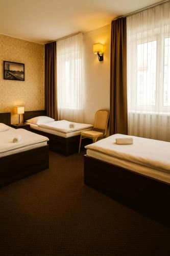 a hotel room with three beds and a window at Aviator Hotel Restauracja & SPA in Pabianice