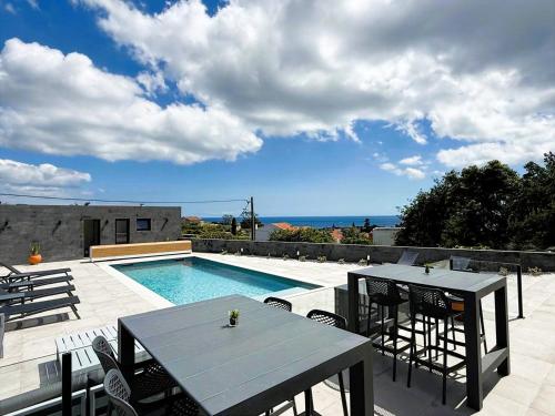 a patio with a table and chairs and a swimming pool at Casa Pura Vida - Heated Pool and Sea View in Ponta Delgada