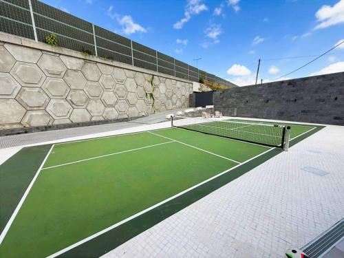 a tennis court with a tennis net on it at Casa Pura Vida - Heated Pool and Sea View in Ponta Delgada