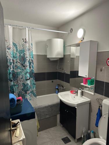 a bathroom with a sink and a shower curtain at Grbavica Apartman in Sarajevo