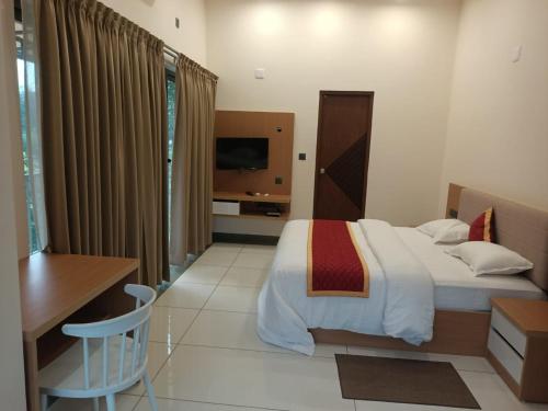 a bedroom with a bed and a desk and a television at Foresta Thattekkadu Pool Resort in Thattakād