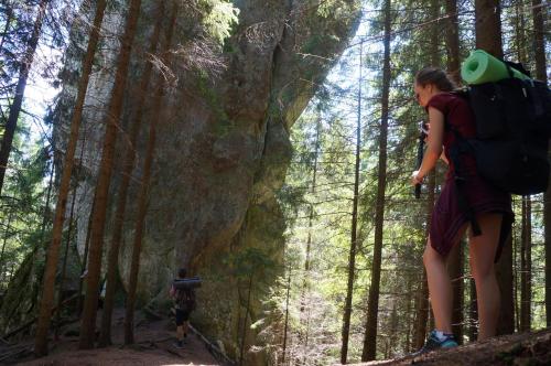 a woman with a backpack walking through a forest at Usadba Okhotnichiy Dvor in Yabluniv