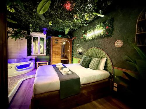 a bedroom with a bed and a tub in a room at Jungle Room Jacuzzi Ambiance Tropicale in Épernay